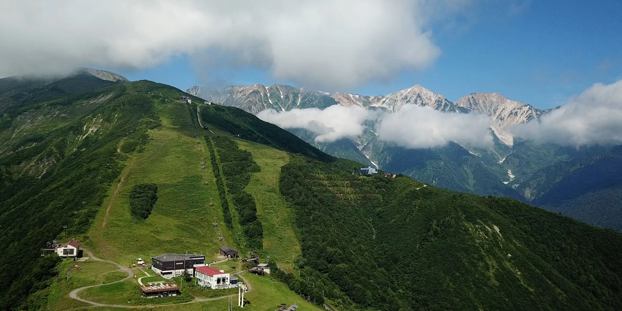 Clouds drifting over the summit station and ski slopes, with Hakuba Sanzan peeking through