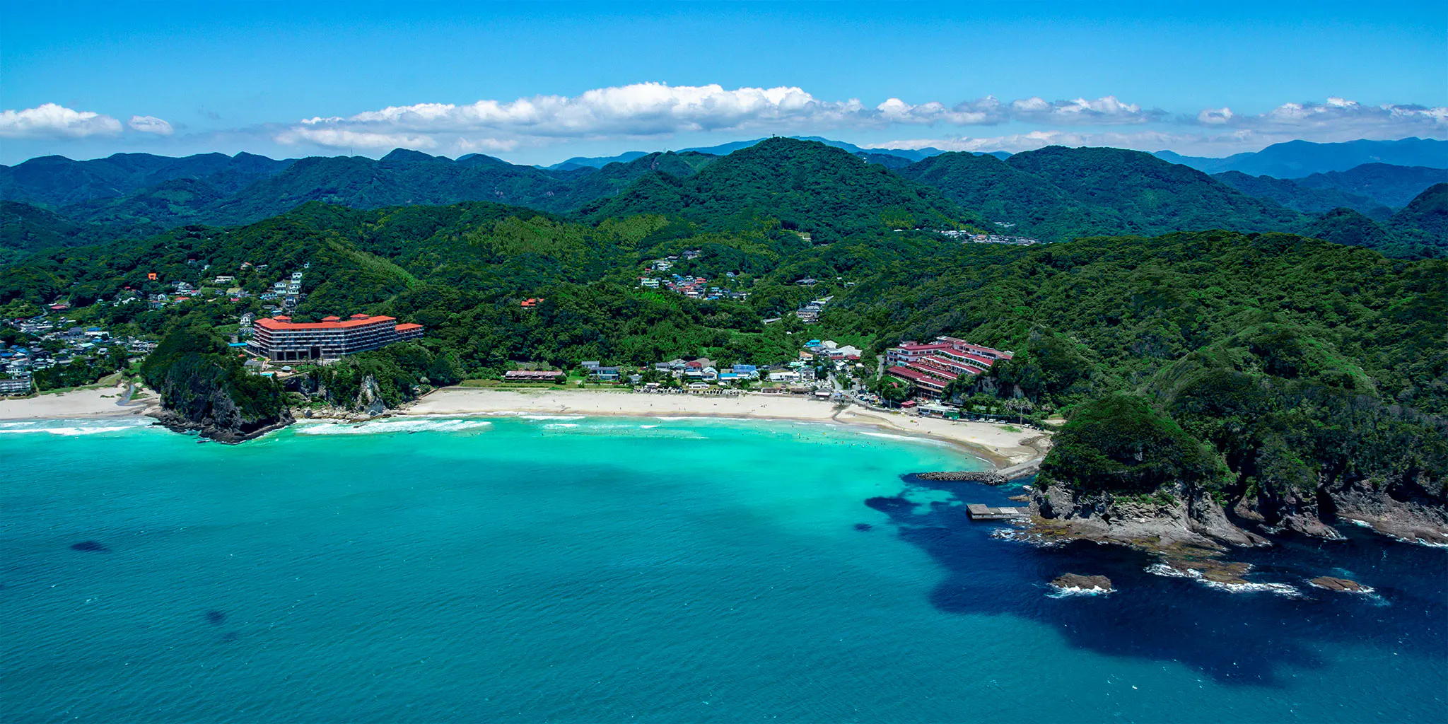 Aerial view of Tatadohama Beach and a bay with an orange-roofed hotel on the cliff