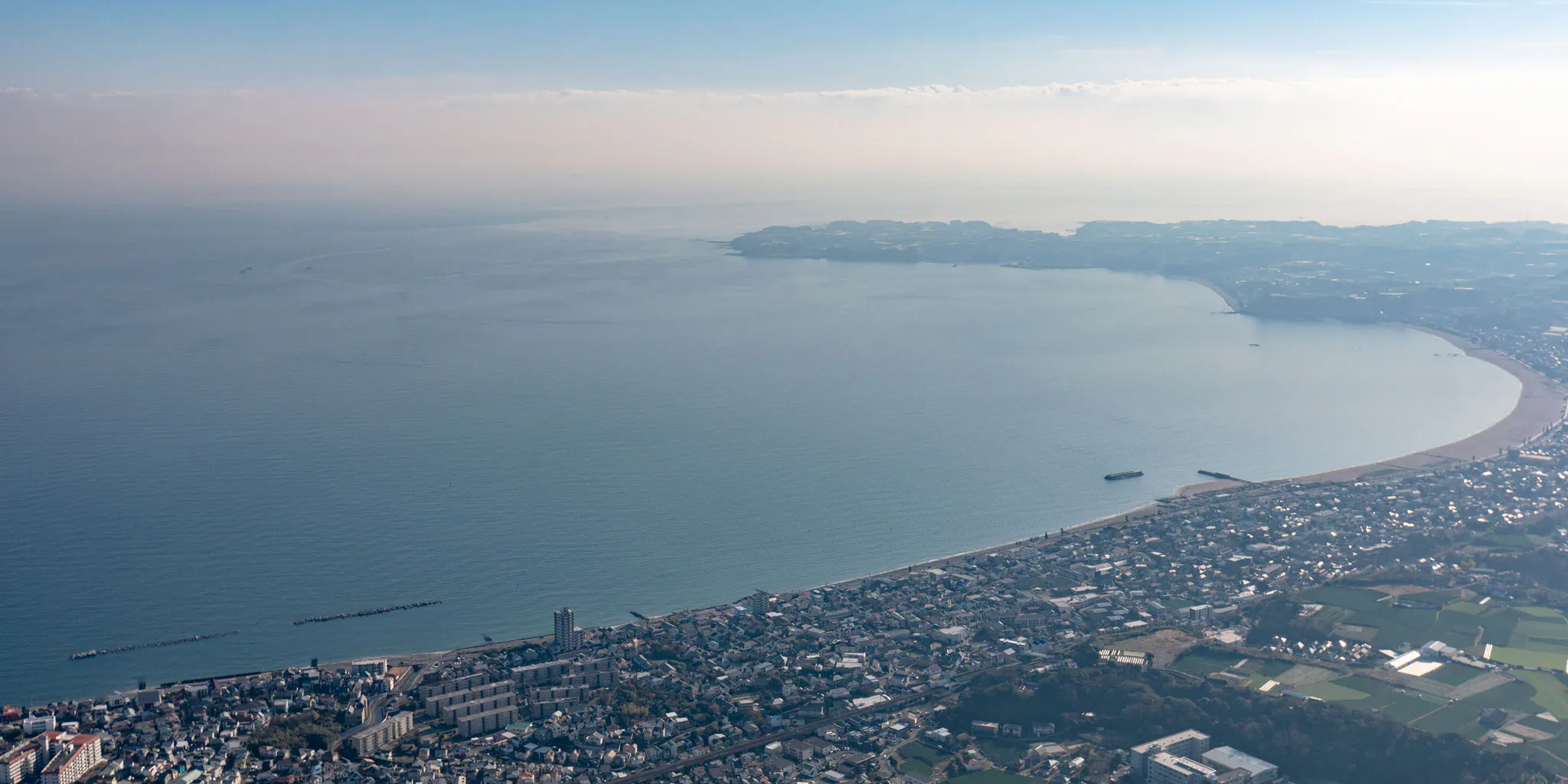 Aerial view of a curving sandy beach coastline on the Miura Peninsula with a distant headland