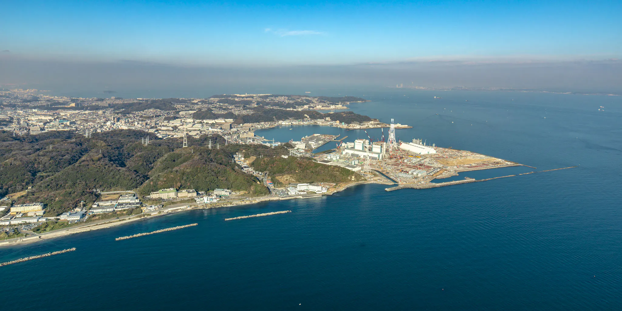 Aerial view of a cape with tall chimneys and cranes from what appears to be a thermal power plant under construction