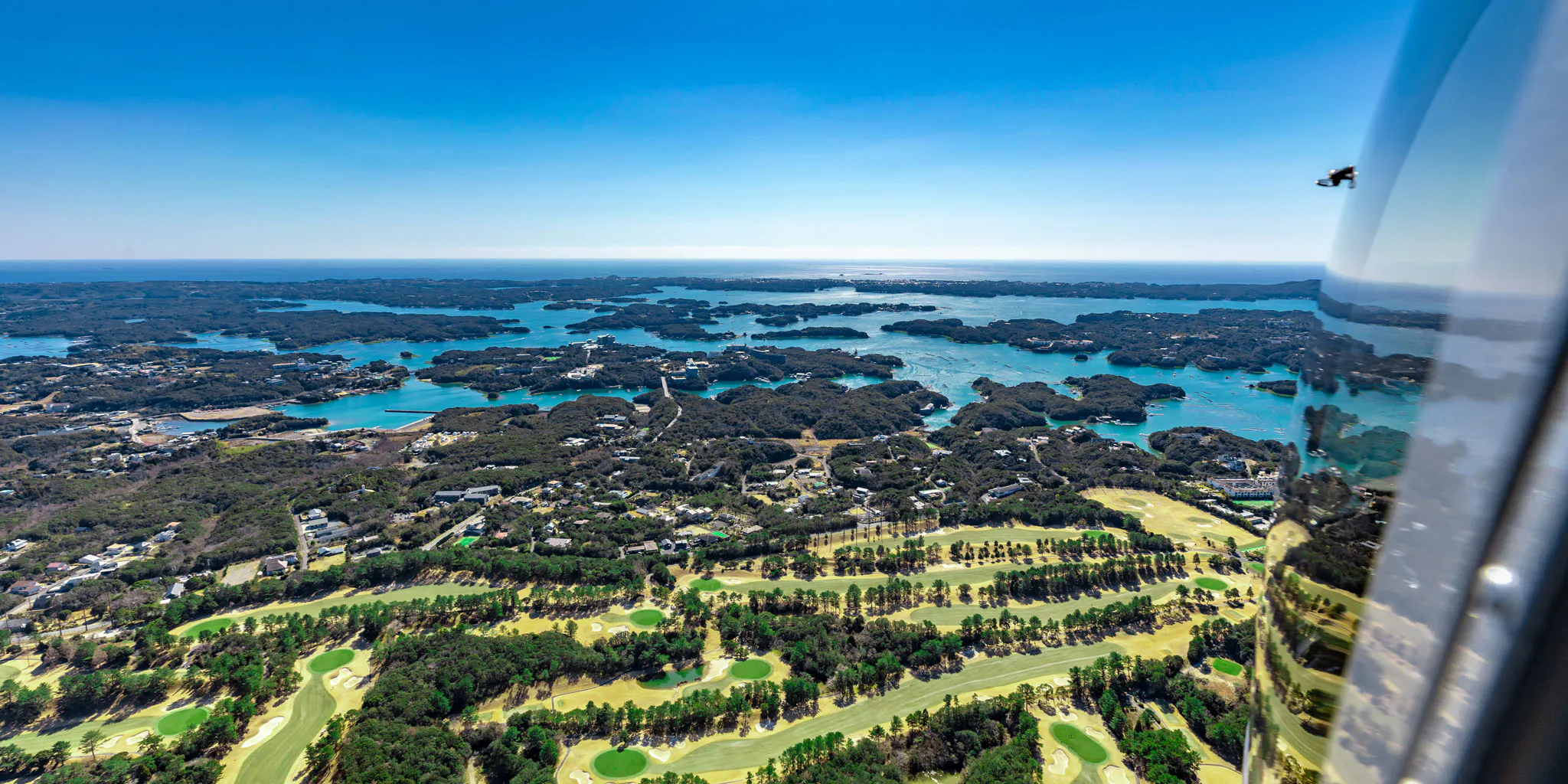 View through the cabin window of a golf course fairway with the ria coastline beyond