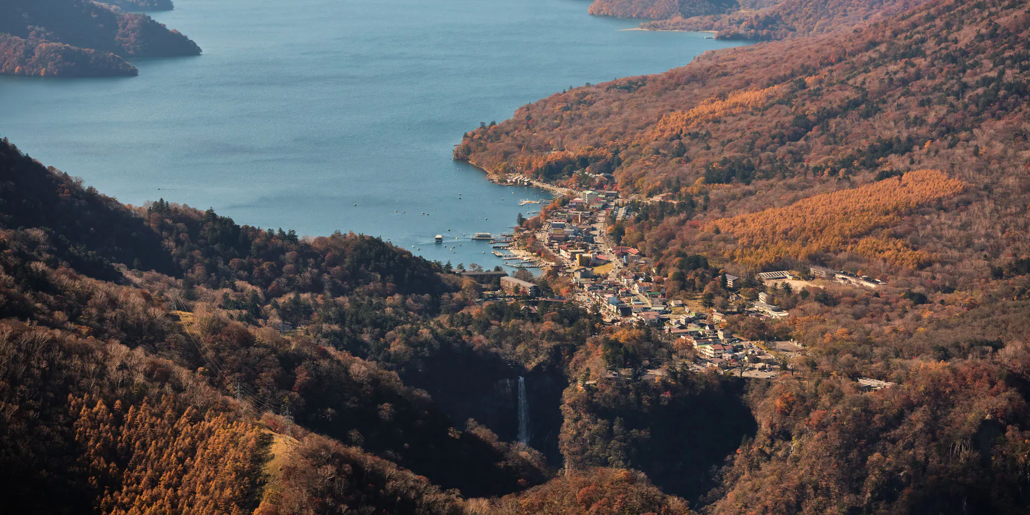 Aerial view of the Lake Chuzenji hot spring town and Kegon Falls surrounded by autumn foliage