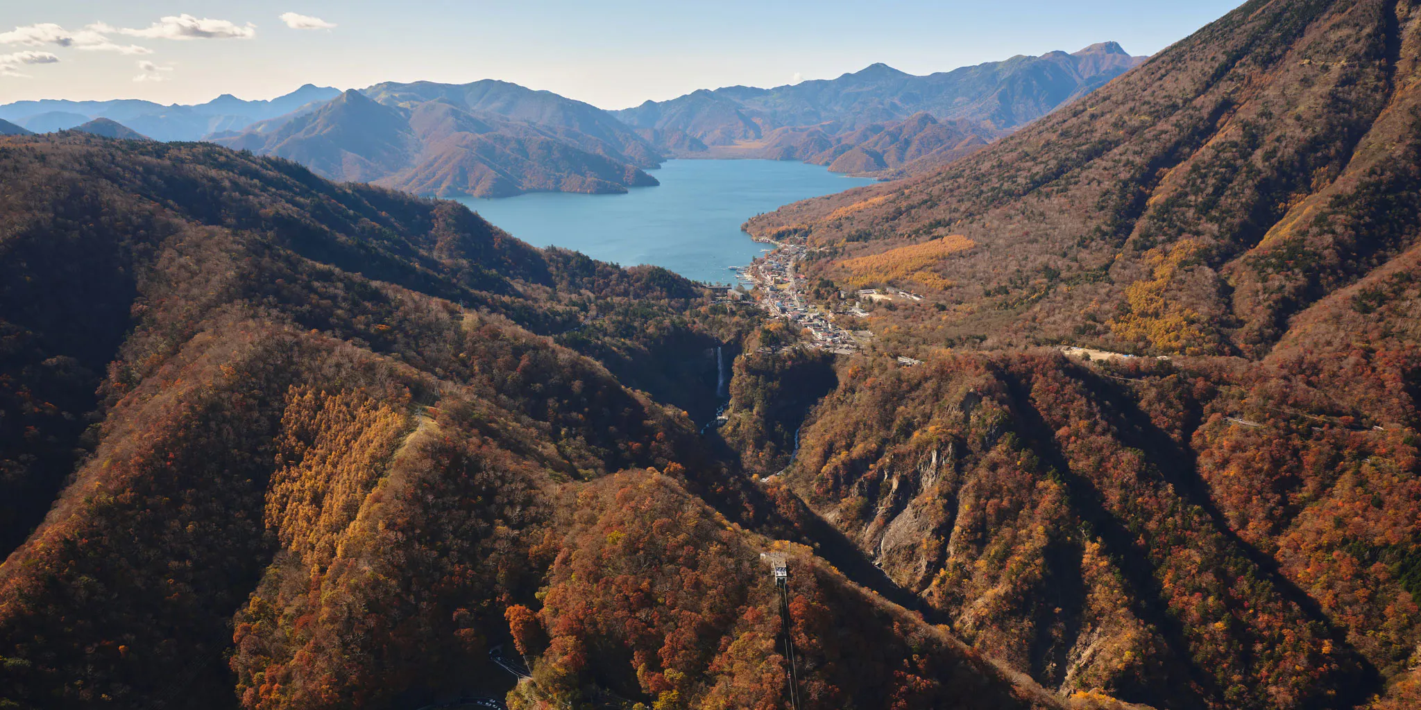 Aerial view of Kegon Falls, a ropeway station, and the Lake Chuzenji hot spring town amid autumn colors